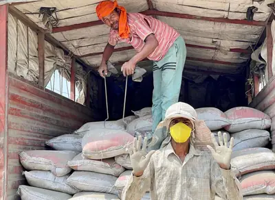 Workers unloading cement bags from a truck at a building site