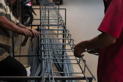 Two workers tying a steel reinforcement cage
